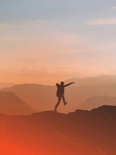 En mann som hopper av glede på fjelltur.