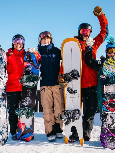 Familie som kjørt snowboard i Hemsedal. De er glade og har hendene i luften