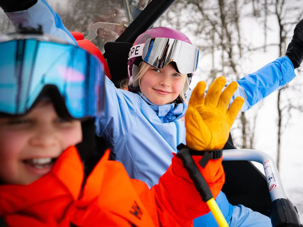en gutt og en jente som sitter i stolheis i Hemsedal skisenter