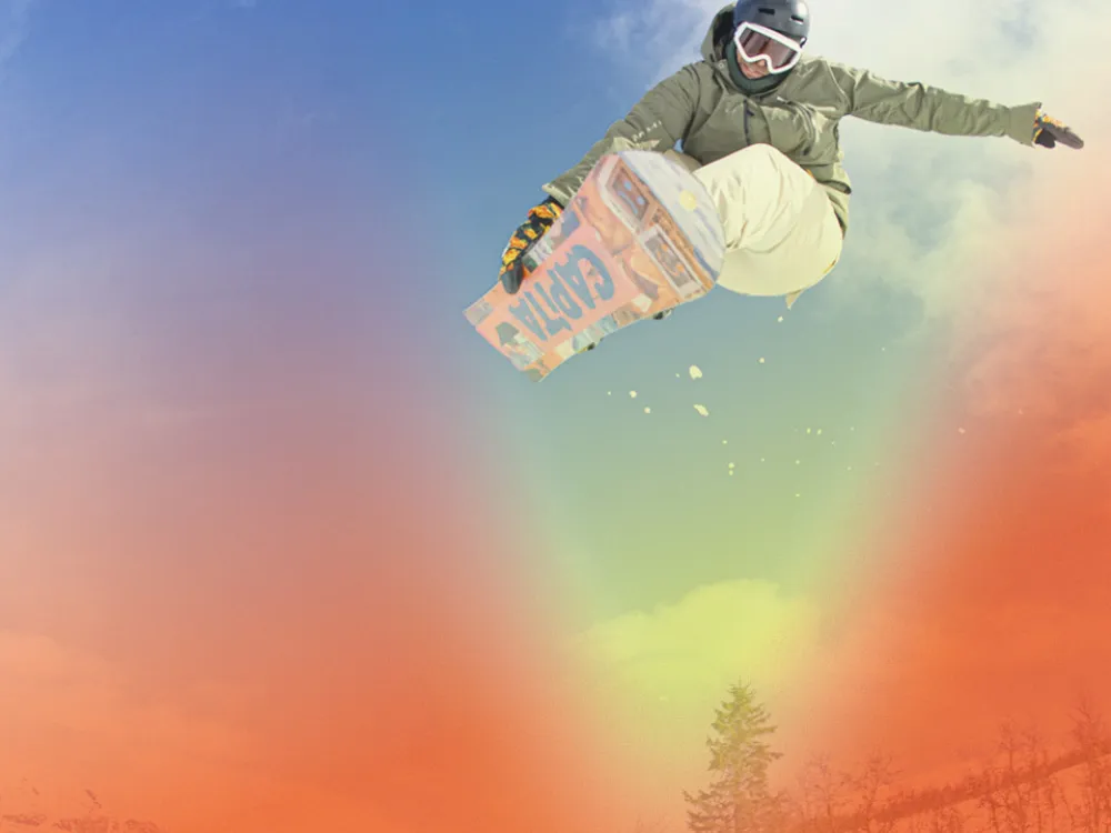 En gutt som tar et triks på snowboard i skibakken.